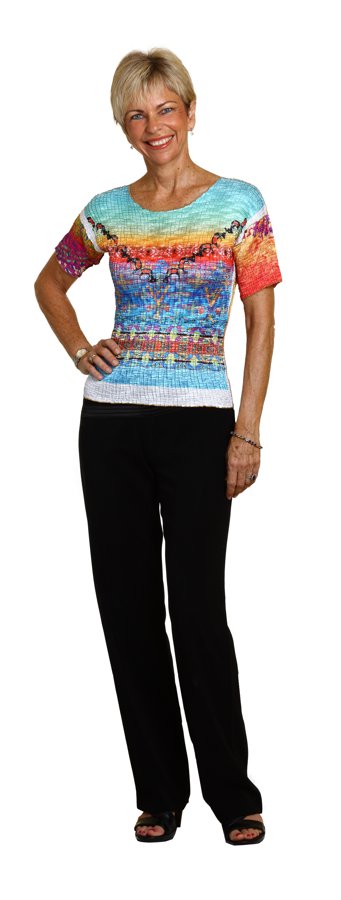 Amanda Gore, full length, hand on hip in a colorful top and black trousers