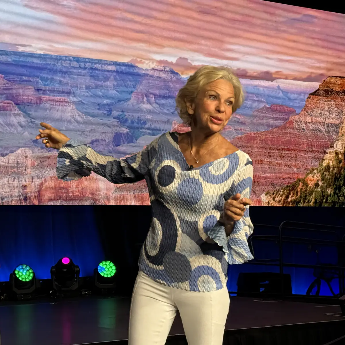 Amanda Gore, leadership keynote speaker, pointing to the audience on stage in front of a canyon backdrop