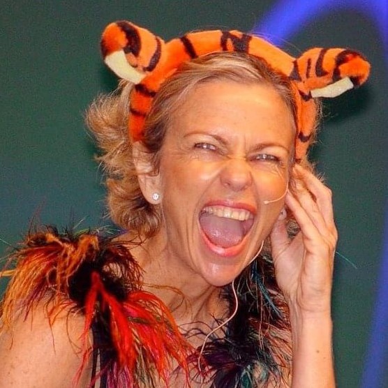 Amanda Gore laughing on stage in Tigger ears and a feather boa