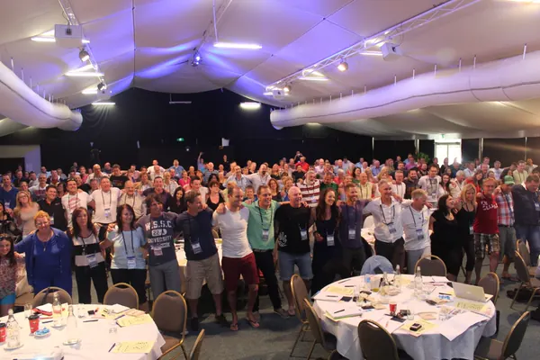 An audience standing with linked arms at an Amanda Gore keynote