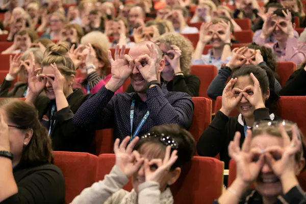 An audience making glasses with their hands at an Amanda Gore keynote