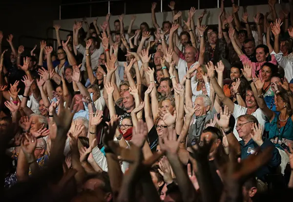 An audience on its feet with arms raised at an Amanda Gore keynote