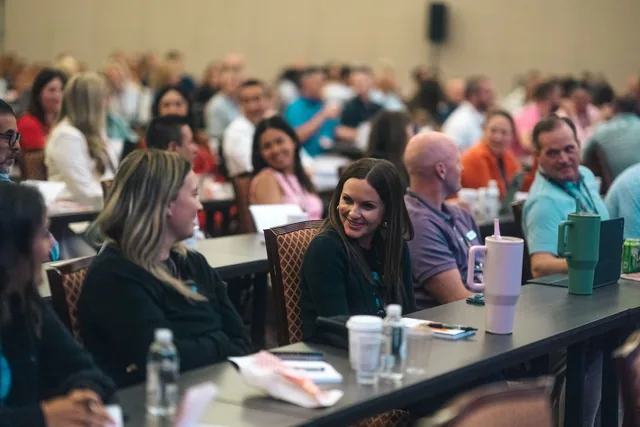 Audience members smiling and turning to each other at an Amanda Gore keynote