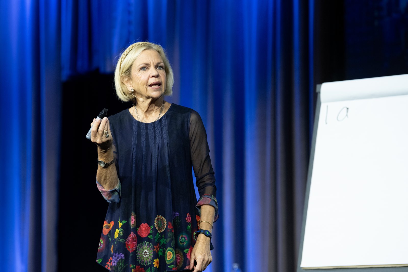 Amanda Gore, leadership keynote speaker, on stage with a marker in her hand beside a flip chart