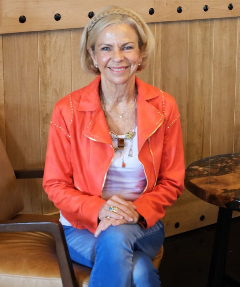 Amanda Gore smiling, seated in an orange jacket