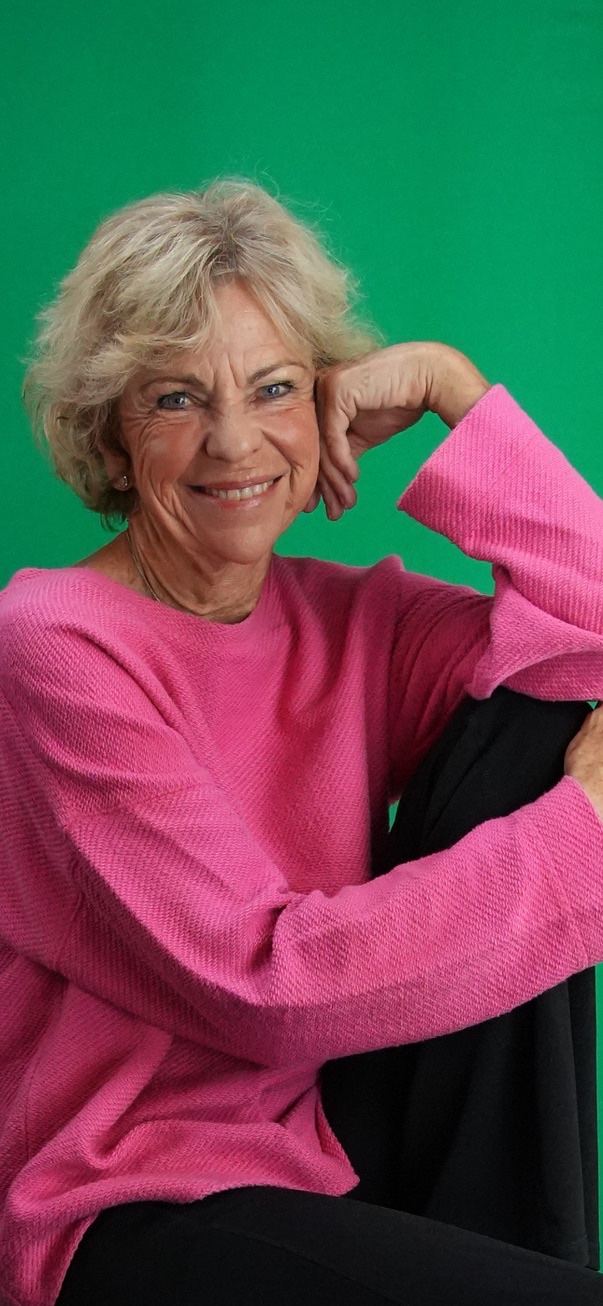 Amanda Gore smiling, resting her cheek on her hand, in a pink sweater
