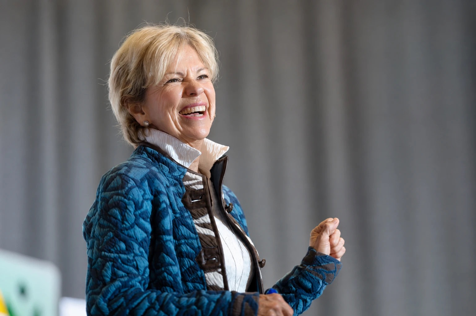 Amanda Gore, leadership speaker, laughing in a blue quilted jacket, one fist raised