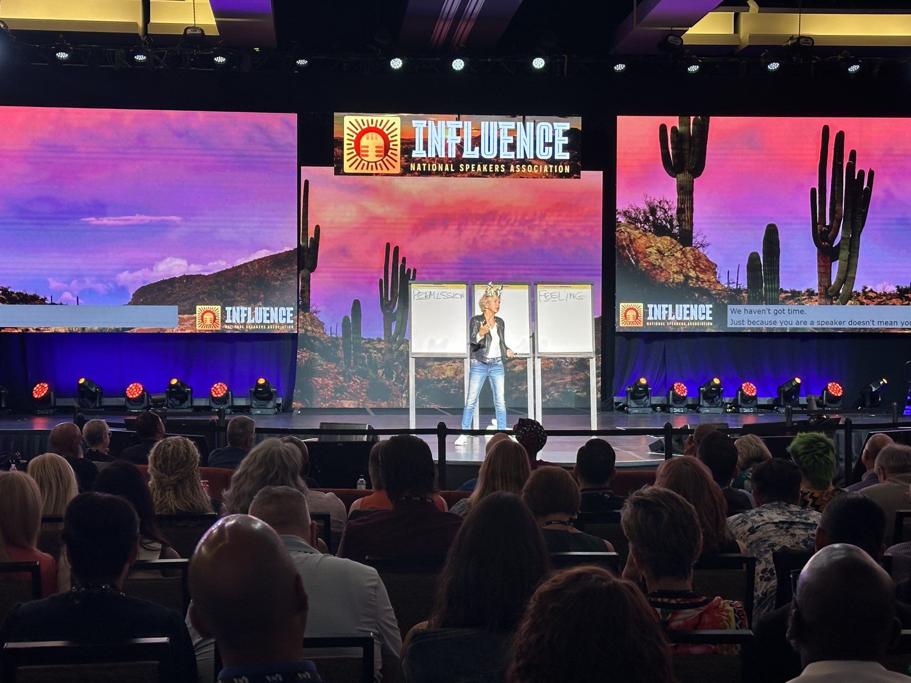 Amanda Gore, leadership speaker, delivering a keynote on the INFLUENCE main stage at the flip charts, with the audience in front of her
