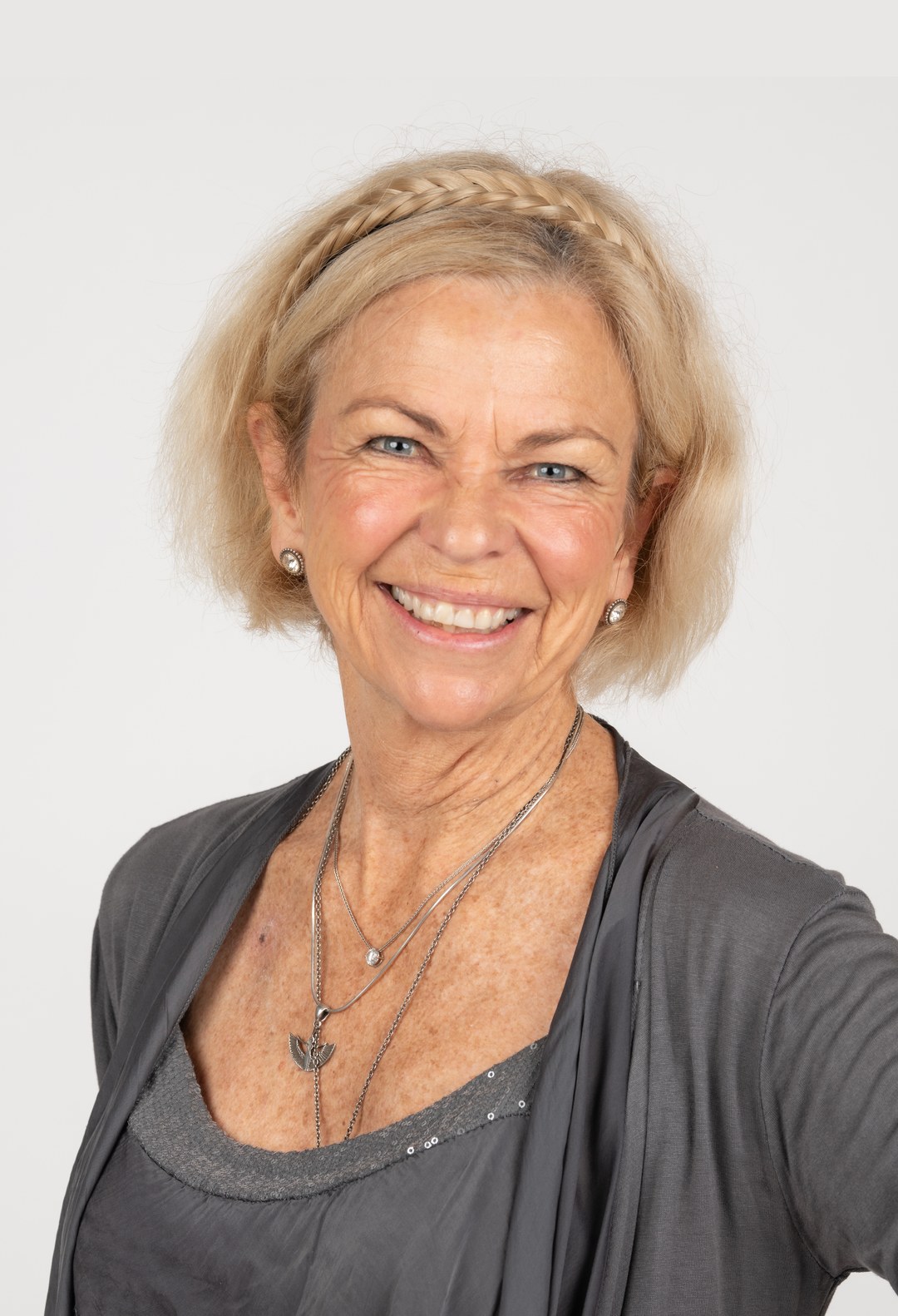 Amanda Gore, leadership keynote speaker, smiling in a grey cardigan with a braided headband