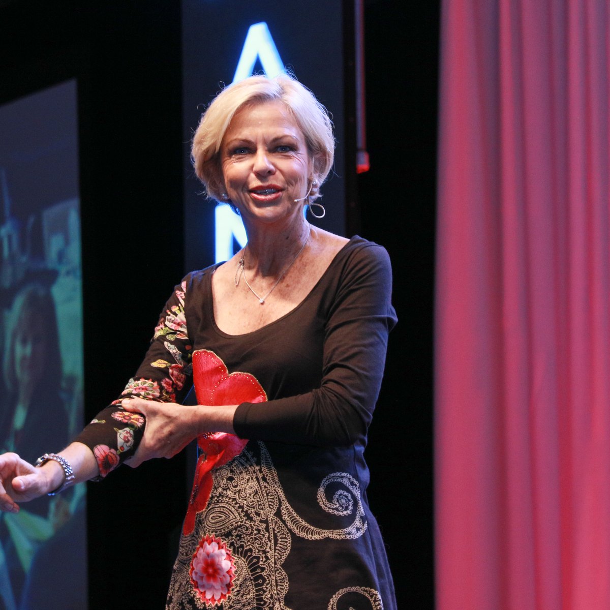 Amanda Gore, leadership keynote speaker, smiling on stage and gesturing with her hands