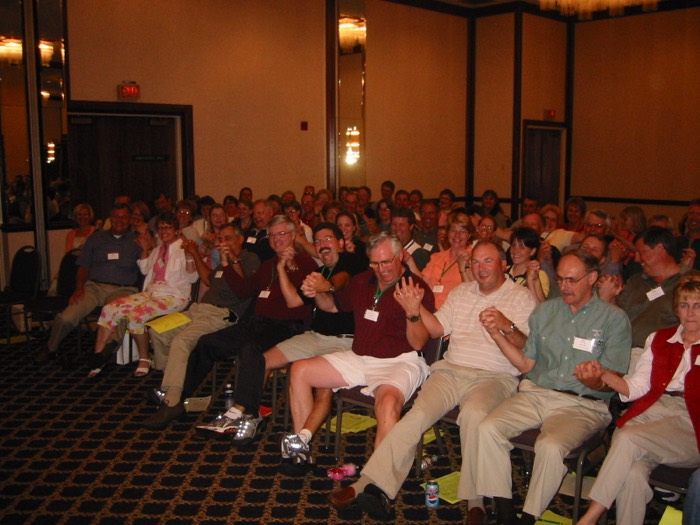 Men in the audience laughing and clapping along at an Amanda Gore keynote