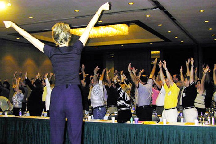 An audience with arms in the air at an Amanda Gore keynote