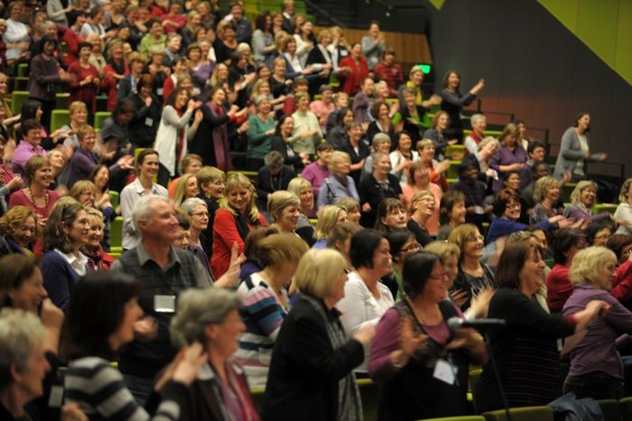 An audience with arms raised at an Amanda Gore keynote