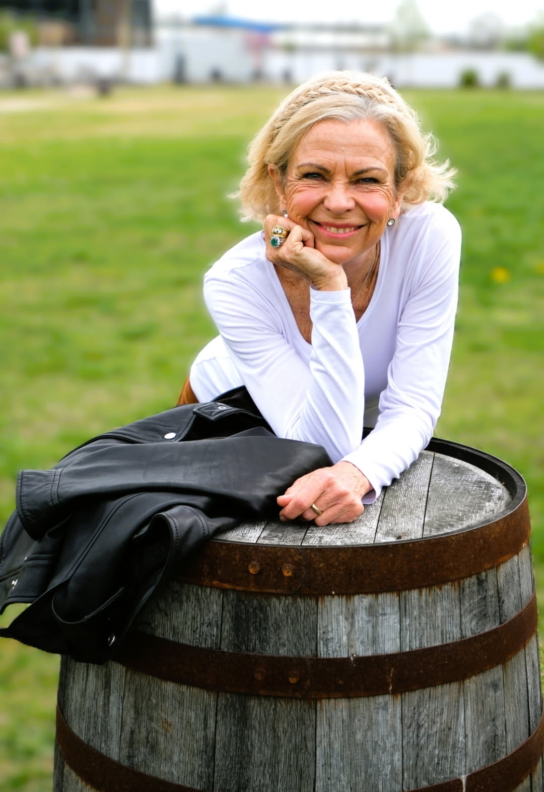 Amanda Gore, leadership speaker, smiling, leaning on a wooden barrel