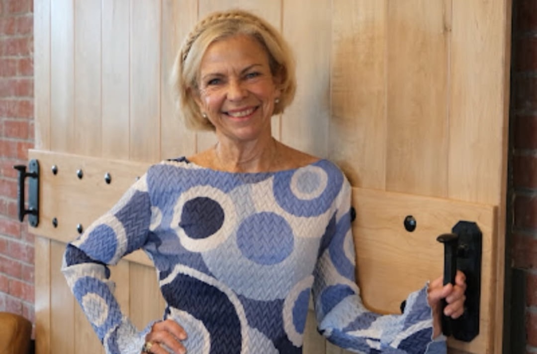 Amanda Gore, leadership speaker, smiling in a patterned top beside a wooden door