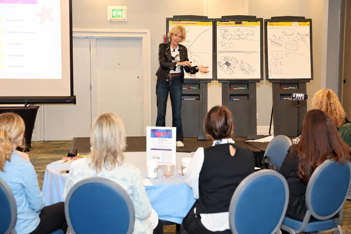 Amanda Gore, leadership keynote speaker, facilitating a small group at round tables beside three flip charts